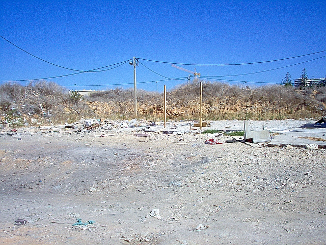 scruffy dry arid wasteland with concrete telegraph poles and rubbish
